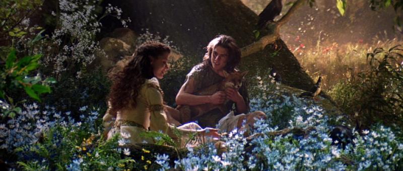 Film still from Ridley Scott's "Legend" Two actors in a forest surrounded by flowers and foliage