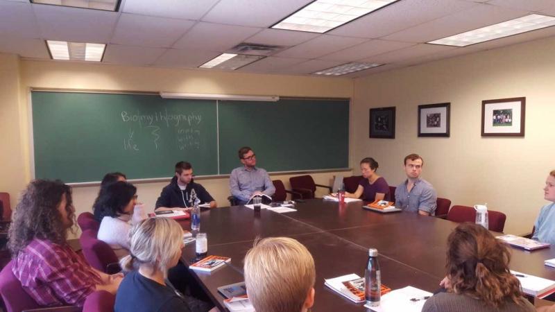 Nick White's Queer Narratives Course students seated around a conference table have discussion