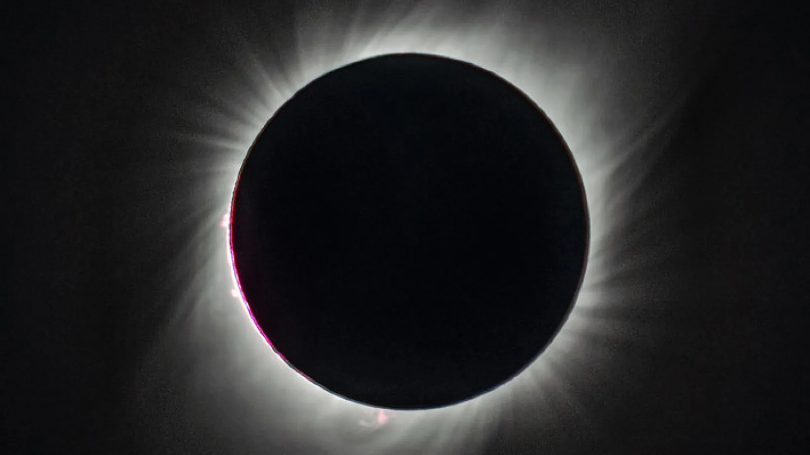 A total eclipse, with the sun's disk entirely covered by the moon, and the sun's corona's showing as bright wisps against the blackness of space