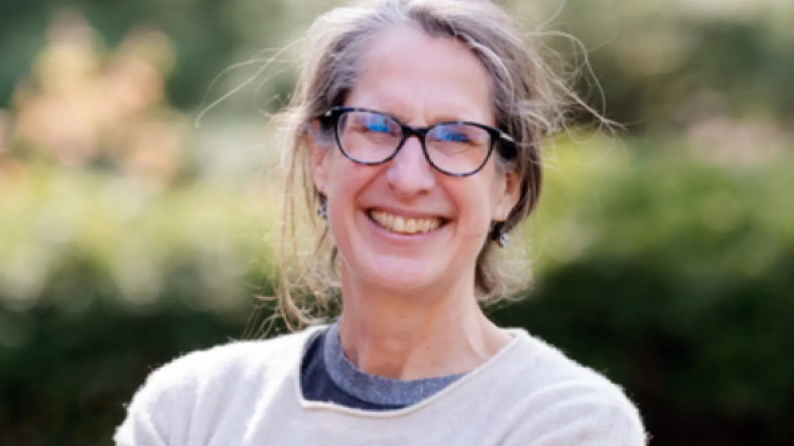 Elizabeth Hewitt smiling in front of some greenery.