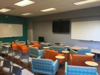 Lounge chairs and plastic chairs set up in an arc in front of whiteboard