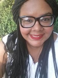 Graduate student Nicole Pizarro smiles in front of a leafy backdrop