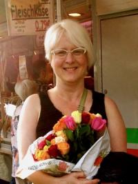 Robyn Warhol smiles while holding a bouquet of multicolored flowers