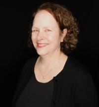 Susan Williams, department chair and professor, poses smiling in front of a black background 