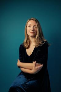 Assistant Professor Zoë Brigley Thompson sits in front of a teal background