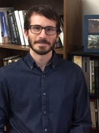 Andrew Bishop in front of a bookshelf
