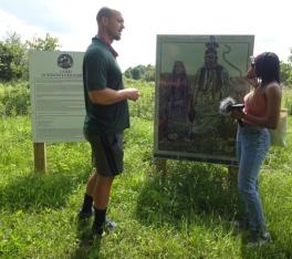 A student interviews a person in front of a land acknowledgment sign 