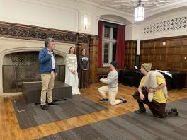 Four actors practice with one another in room with fire place.