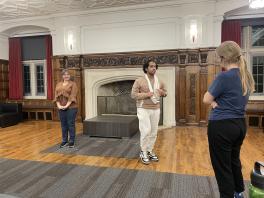 Three actors rehearse in front of a large fireplace 