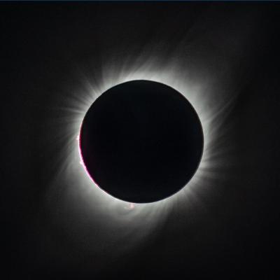 A total eclipse, with the sun's disk entirely covered by the moon, and the sun's corona's showing as bright wisps against the blackness of space