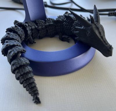 Black 3D printed dragon on top of a roll of masking tape