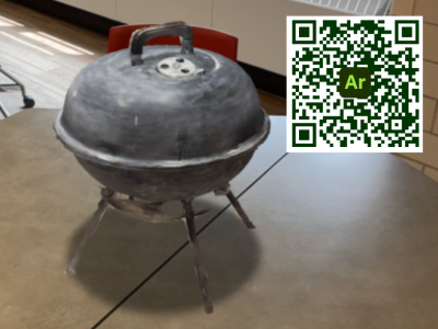 A 3D model of a gray charcoal grill on a table, as seen on a mobile device.
