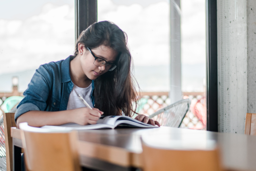 Student writing at a table