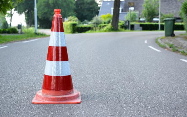 Orange traffic cone with white stripes on an asphalt street