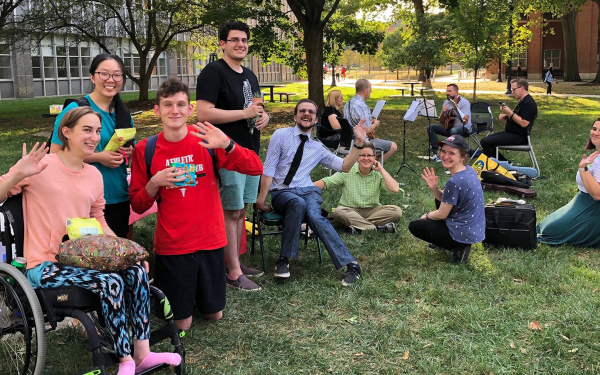 Group of people smiling and waving at the camera