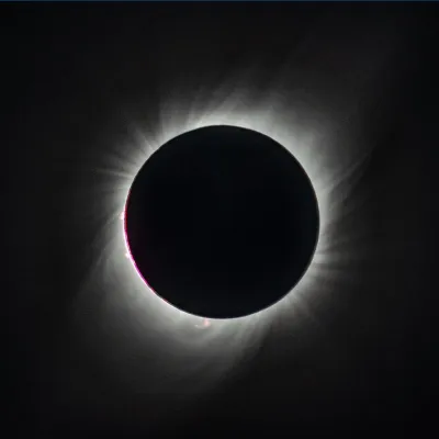 A total eclipse, with the sun's disk entirely covered by the moon, and the sun's corona's showing as bright wisps against the blackness of space