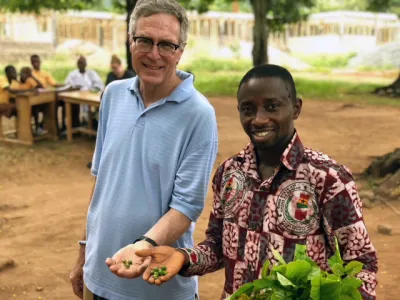 Two men hold seeds in their hands