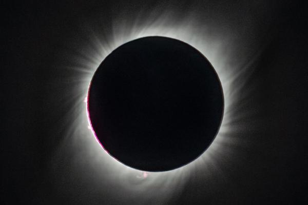 A total eclipse, with the sun's disk entirely covered by the moon, and the sun's corona's showing as bright wisps against the blackness of space