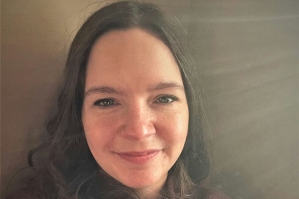 Dr. Elisabeth Miller, a white woman with brown hair wearing a burgundy-colored sweater, smiles into the camera.