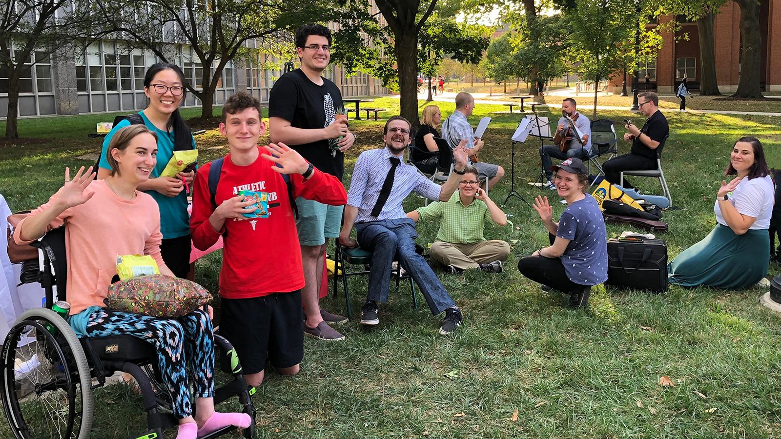 Group of people smiling and waving at the camera