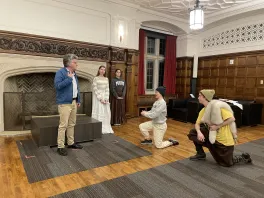 Four actors practice with one another in room with fire place.